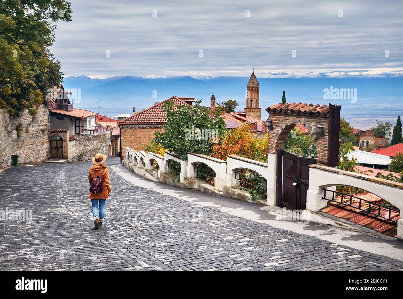 Touristische Frau in Hut mit Rucksack an der Straße von signagi Stadt in Georgien Stockfoto