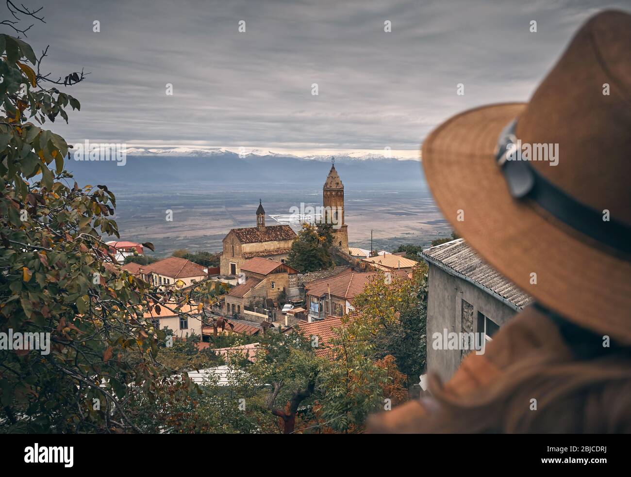 Alte Kirche mit Turm in Signagi Stadt am grauen bewölkten Himmel und Frau in hat sich in Georgien Stockfoto