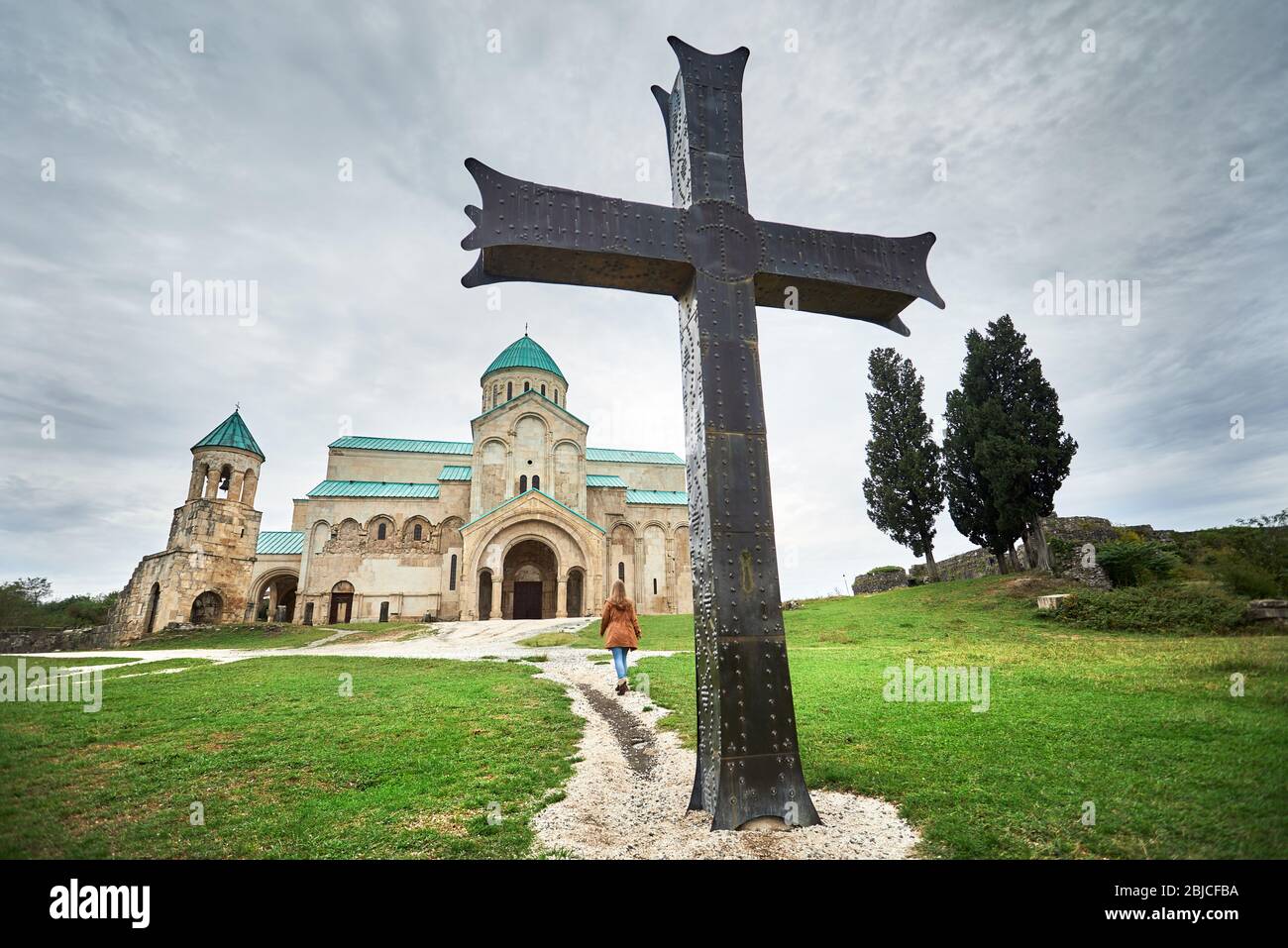 Frau Fuß zu Bagrati Kirche mit großen eisernen Kreuz bei bedecktem Himmel in Kutaissi, Georgien Stockfoto