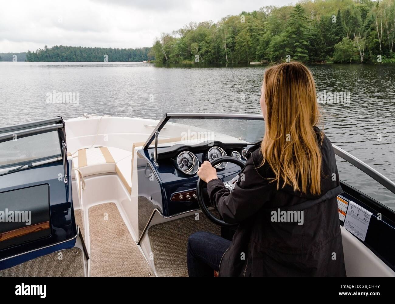 Junge Frau, die ein Motorboot fahren Stockfoto