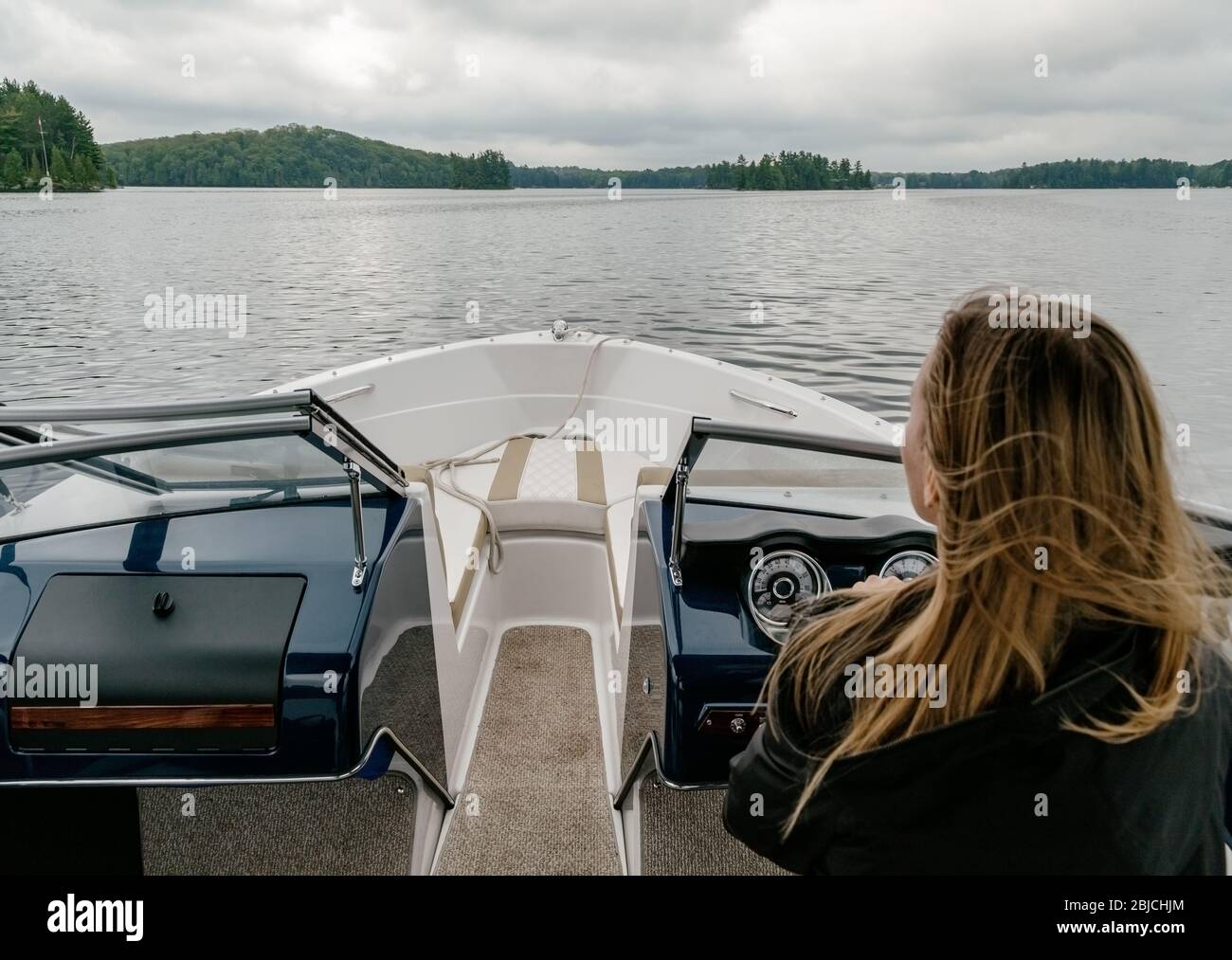 Junge Frau, die ein Motorboot fahren Stockfoto