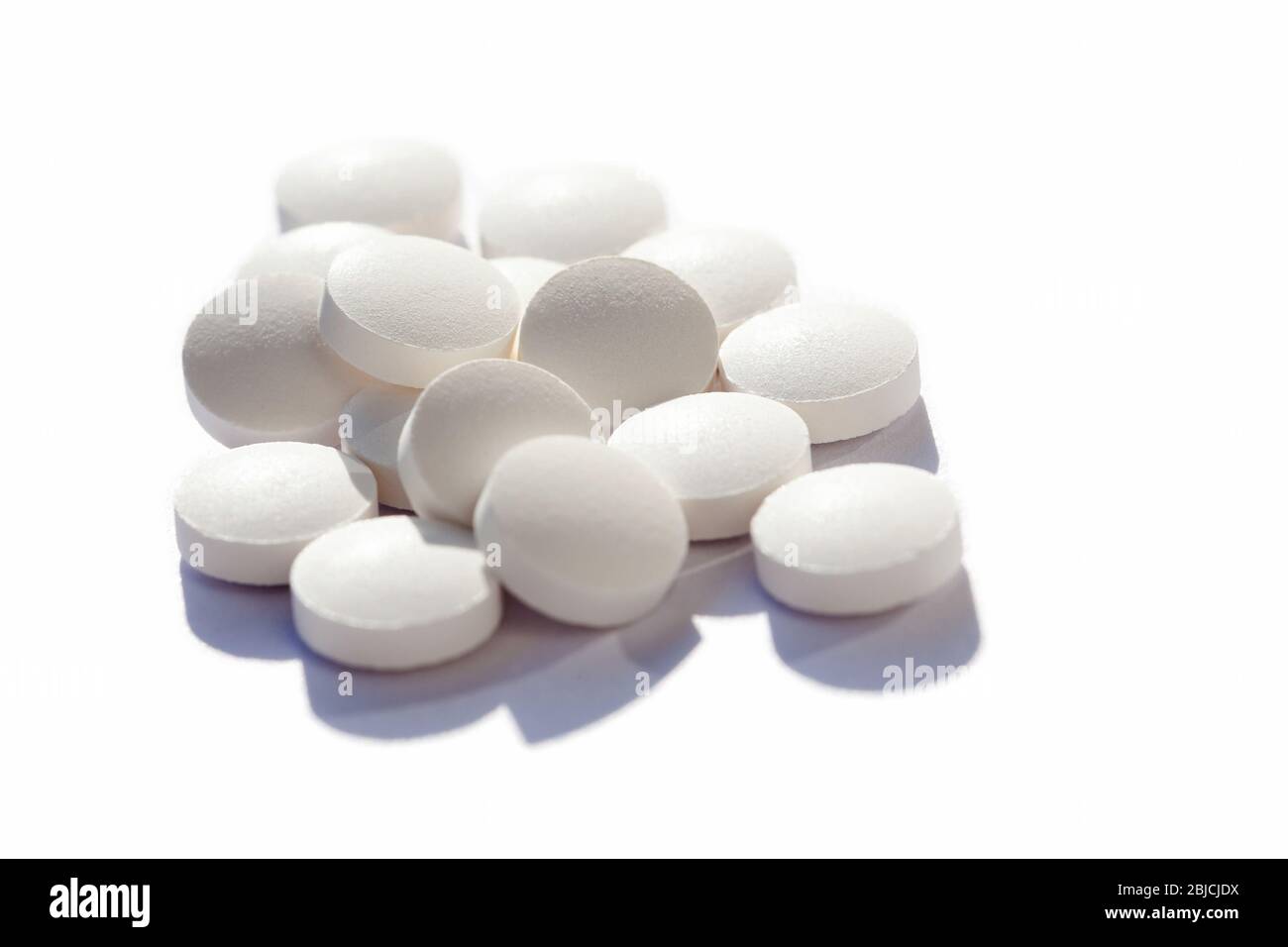 Viele generische kleine runde weiße Pillen, viele kleine Tabletten auf weißem Hintergrund Nahaufnahme. Einfache Gruppe von kleinen Pillen, Medizin, Medikamente und Medikamente Stockfoto
