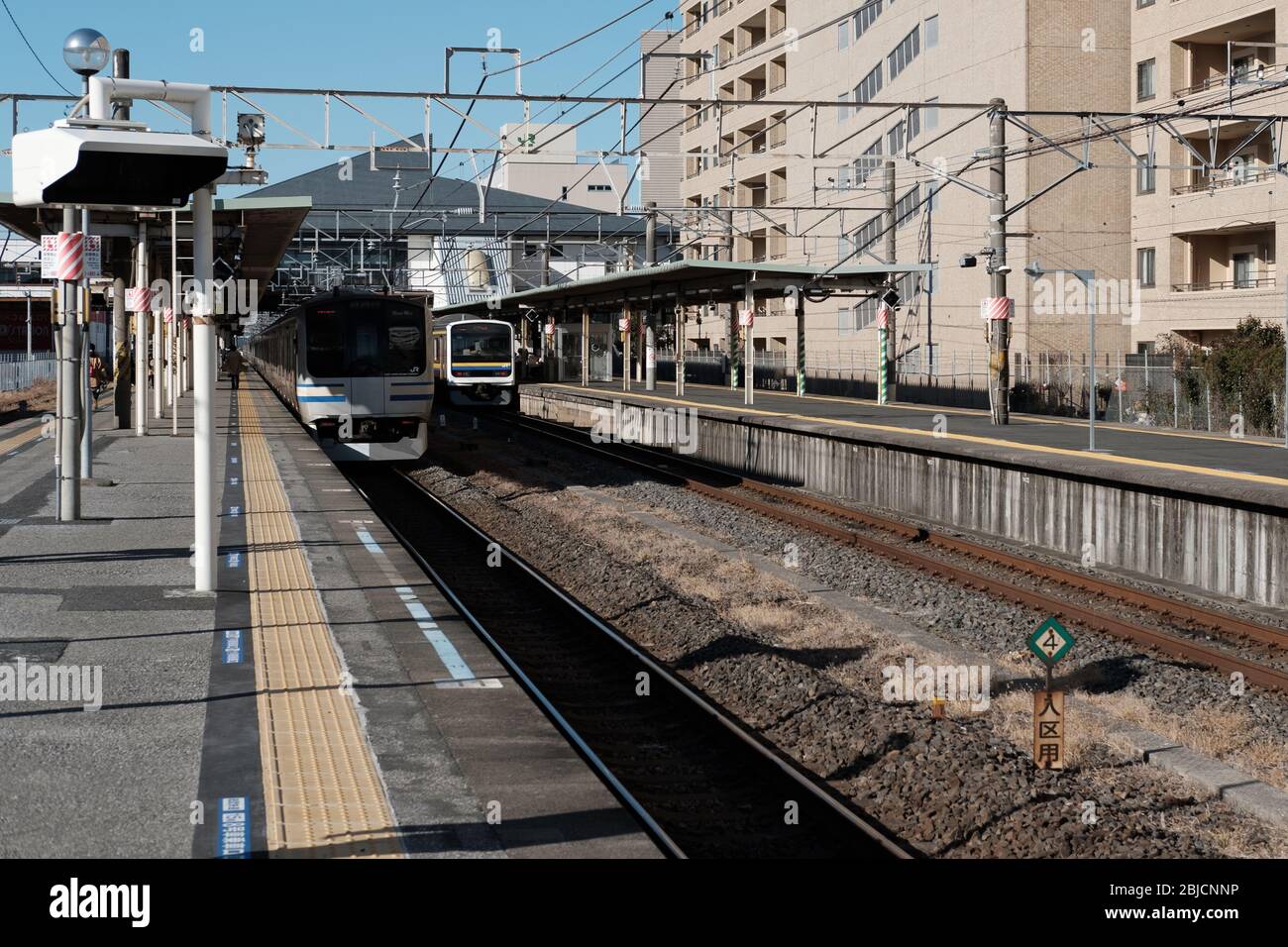 CHIBA, JAPAN - JANUAR 19 2019: Die Vorderansicht des Zuges hält und der Mann, der auf dem Bahnsteig an einem ländlichen Bahnhof läuft. Stockfoto