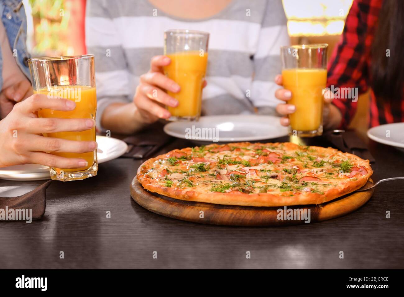 Freunde sitzen am Tisch mit Orangensaft und leckere Pizza, aus der Nähe Stockfoto