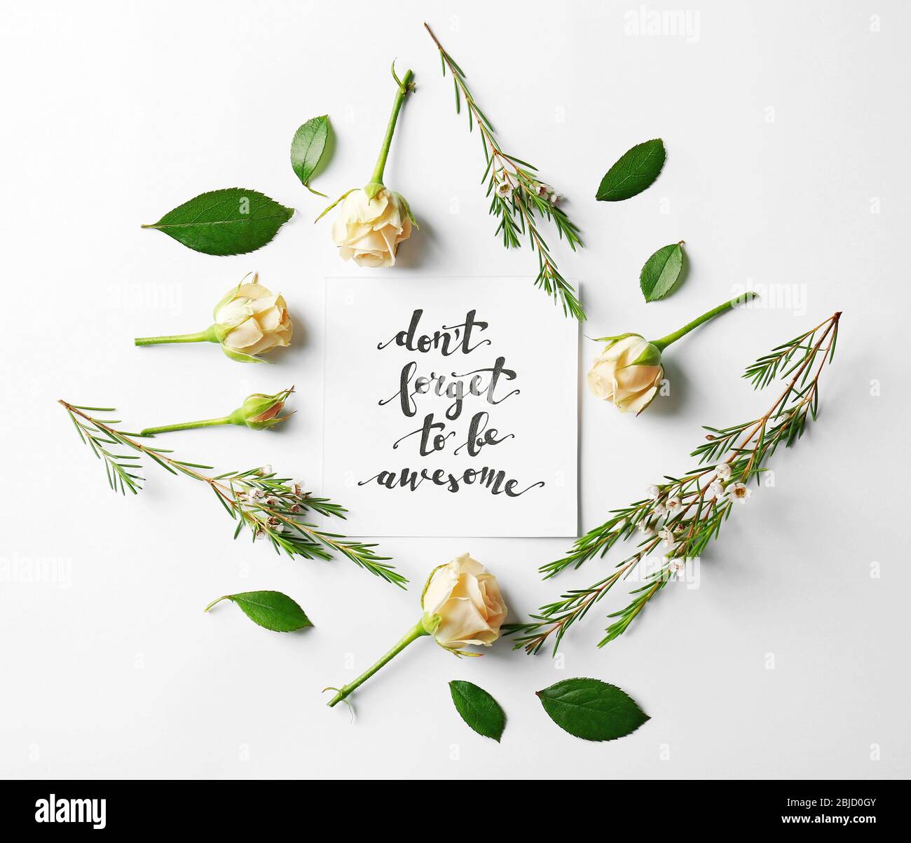 Zitat 'Don't forget to be awesome' auf Papier mit Rosen und Blättern auf weißem Hintergrund geschrieben. Draufsicht Stockfoto