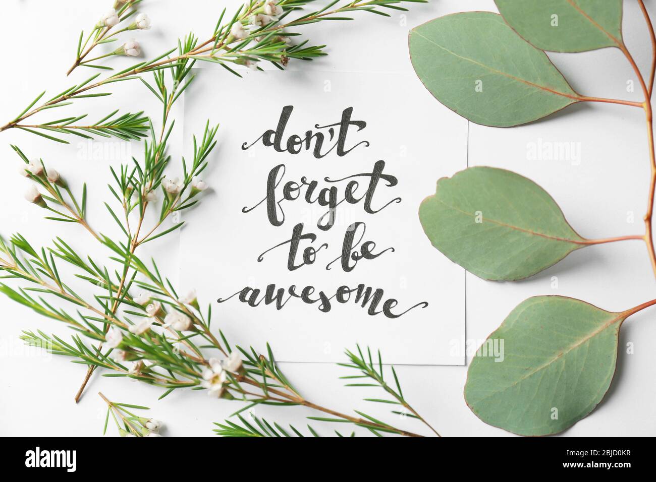 Zitat 'Don't forget to be awesome' auf Papier geschrieben mit Blättern und Blumen auf weißem Hintergrund. Draufsicht Stockfoto