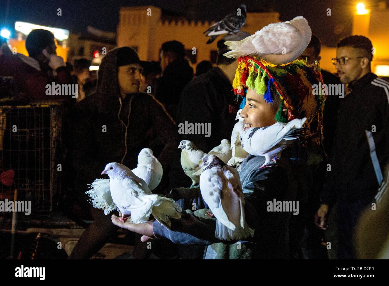 Mädchen mit Tauben bedeckt auf Jemaa el-Fnaa Markt in der Nacht, Marrakesch, Marokko Stockfoto