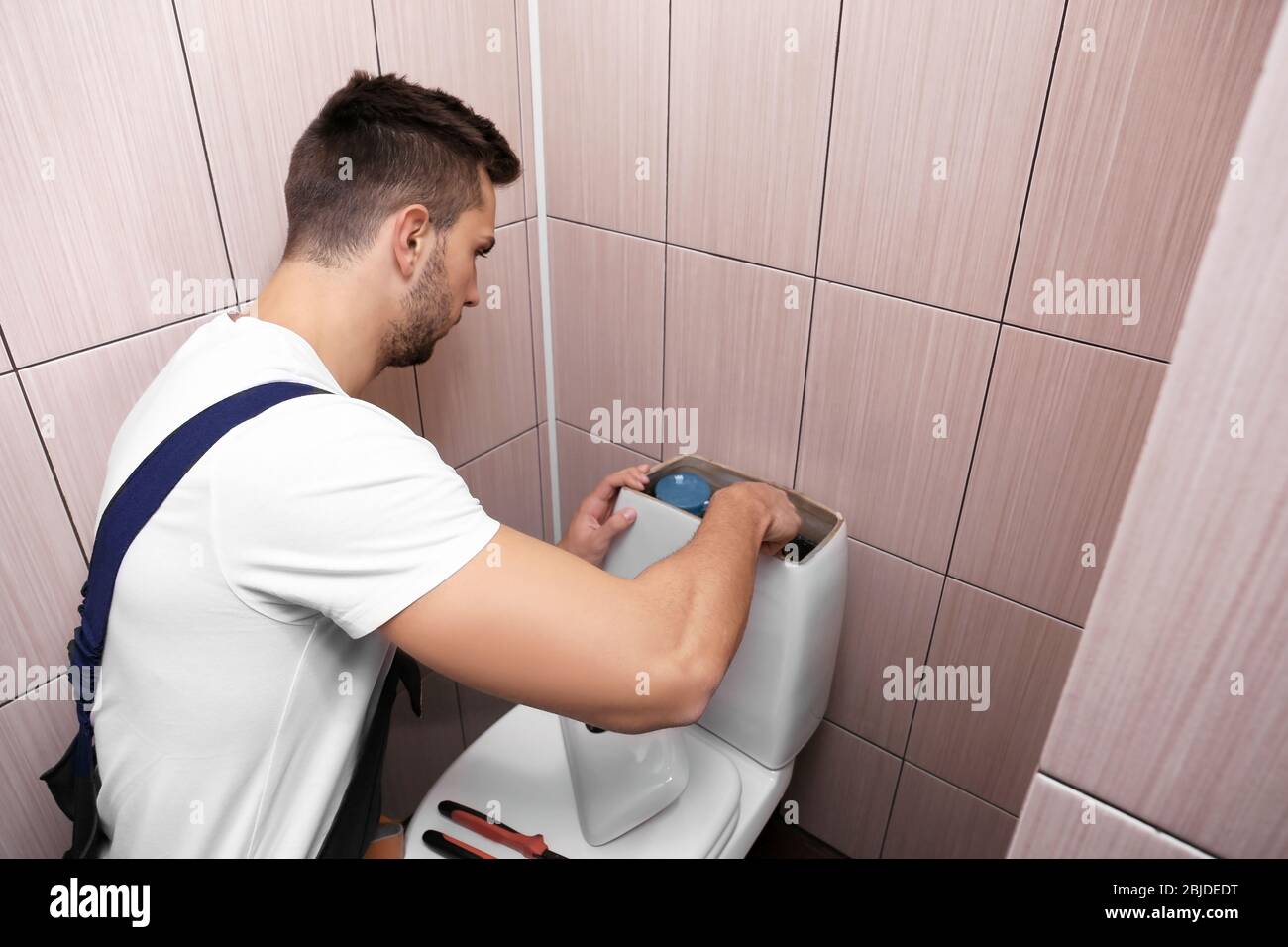 Klempner repariert die Toilettenzisterne am Wasserschrank Stockfoto