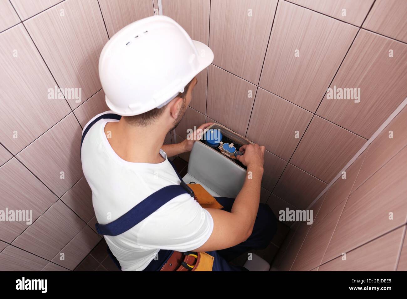 Klempner repariert die Toilettenzisterne am Wasserschrank Stockfoto