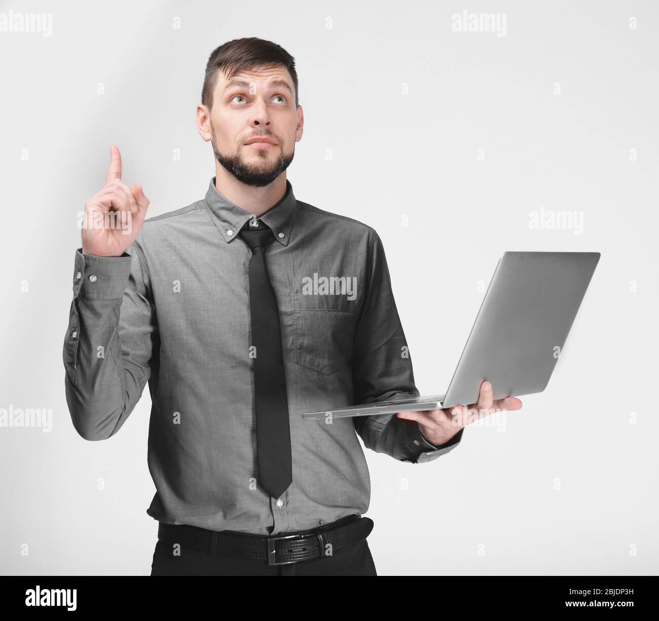 Schöner junger Programmierer mit Laptop auf farbigem Hintergrund Stockfoto