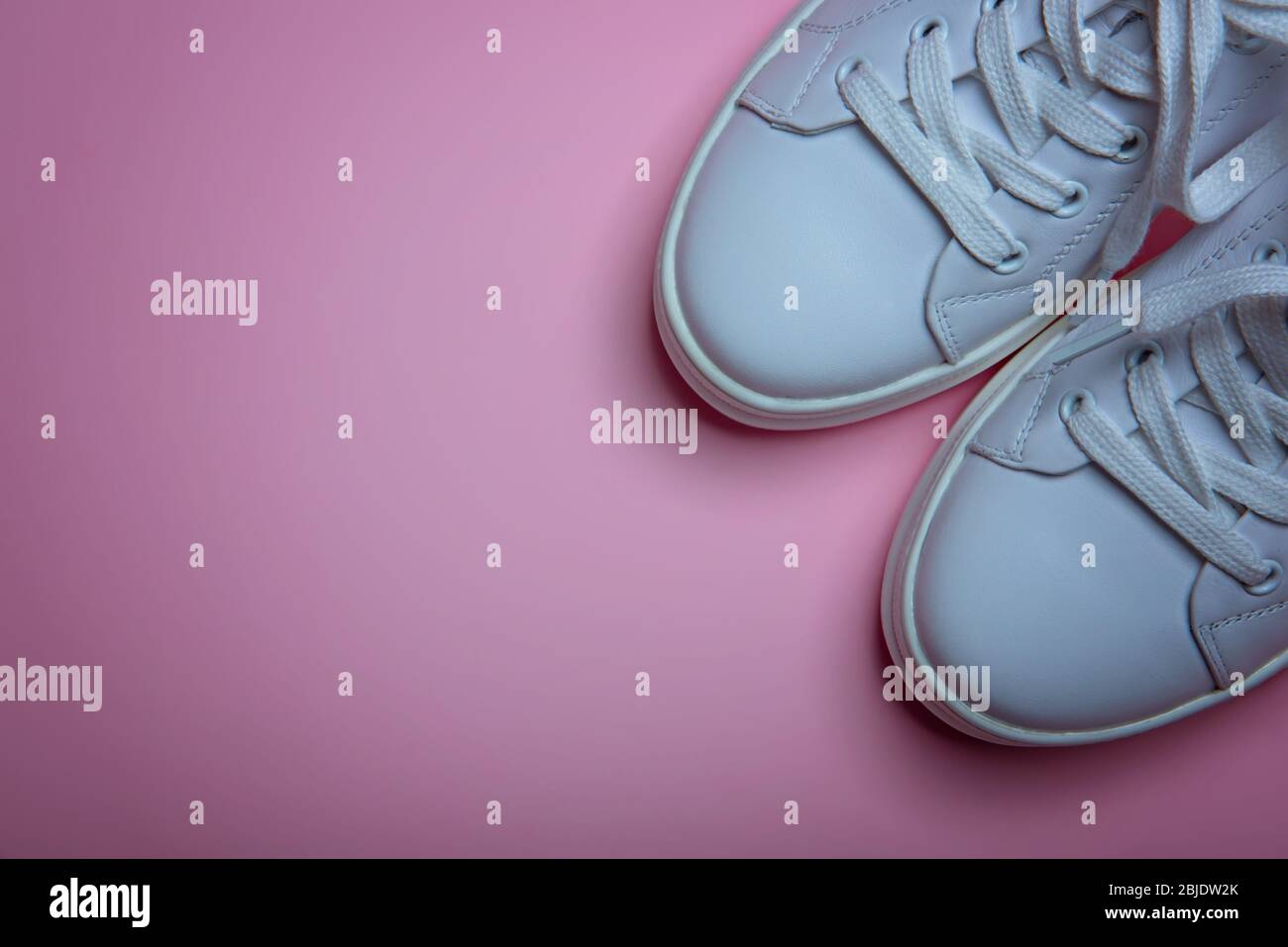 Weiße Sneaker auf dem hellrosa Hintergrund. Flaches Lay. Kopierbereich. Ort für Text.Abstraktes Surrealismus und Minimalismus Shopping Konzept. Stockfoto