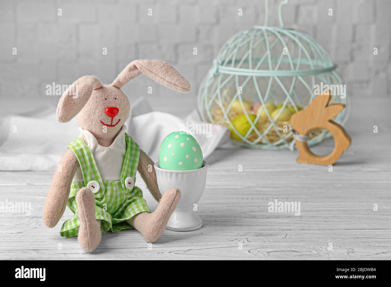 Schöner Hase und Osterei auf weißem Holztisch Stockfoto