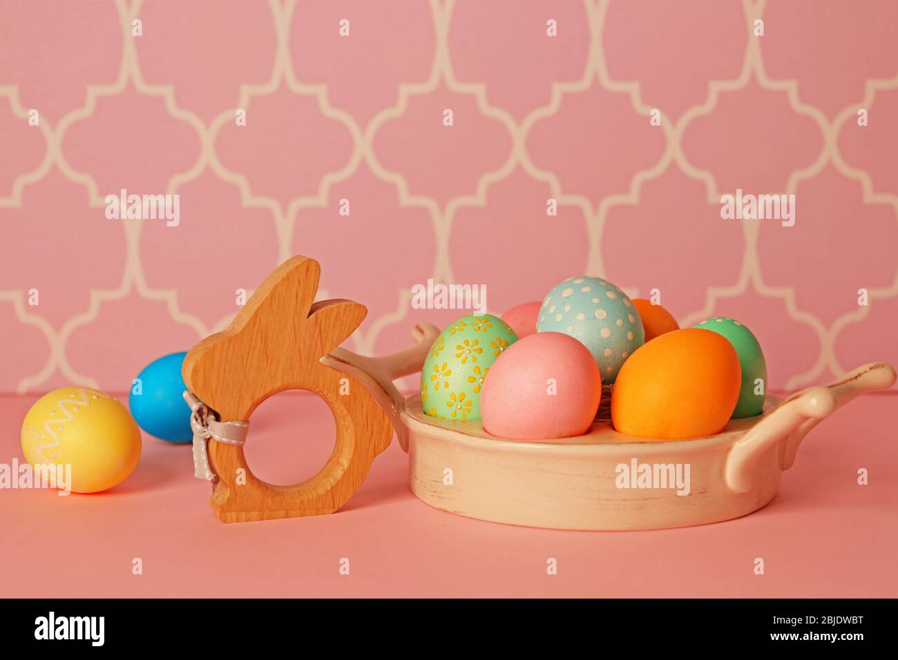 Ostereier und Hasenfigur auf rosa Tisch Stockfoto