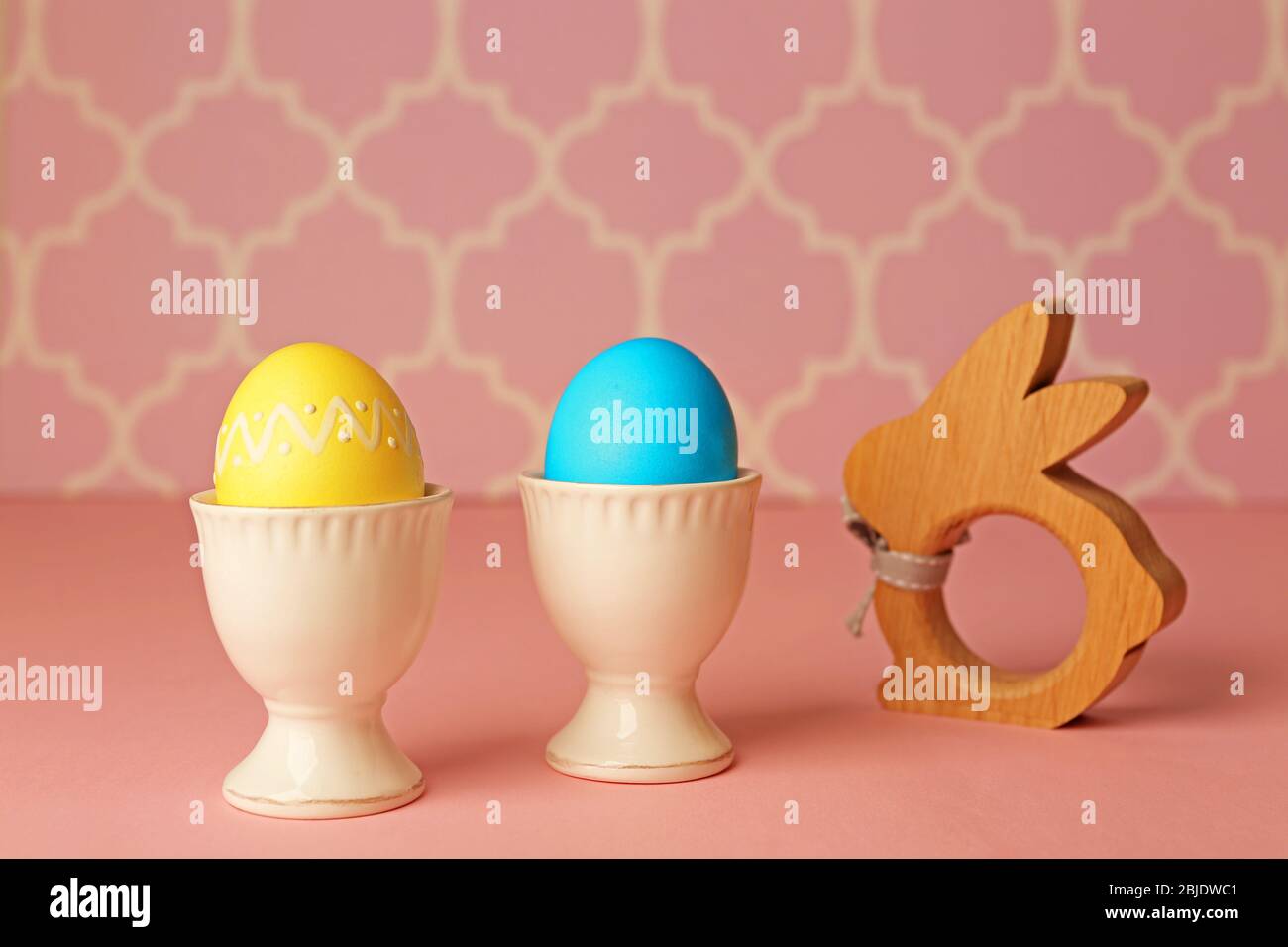 Ostereier und Hasenfigur auf rosa Tisch Stockfoto