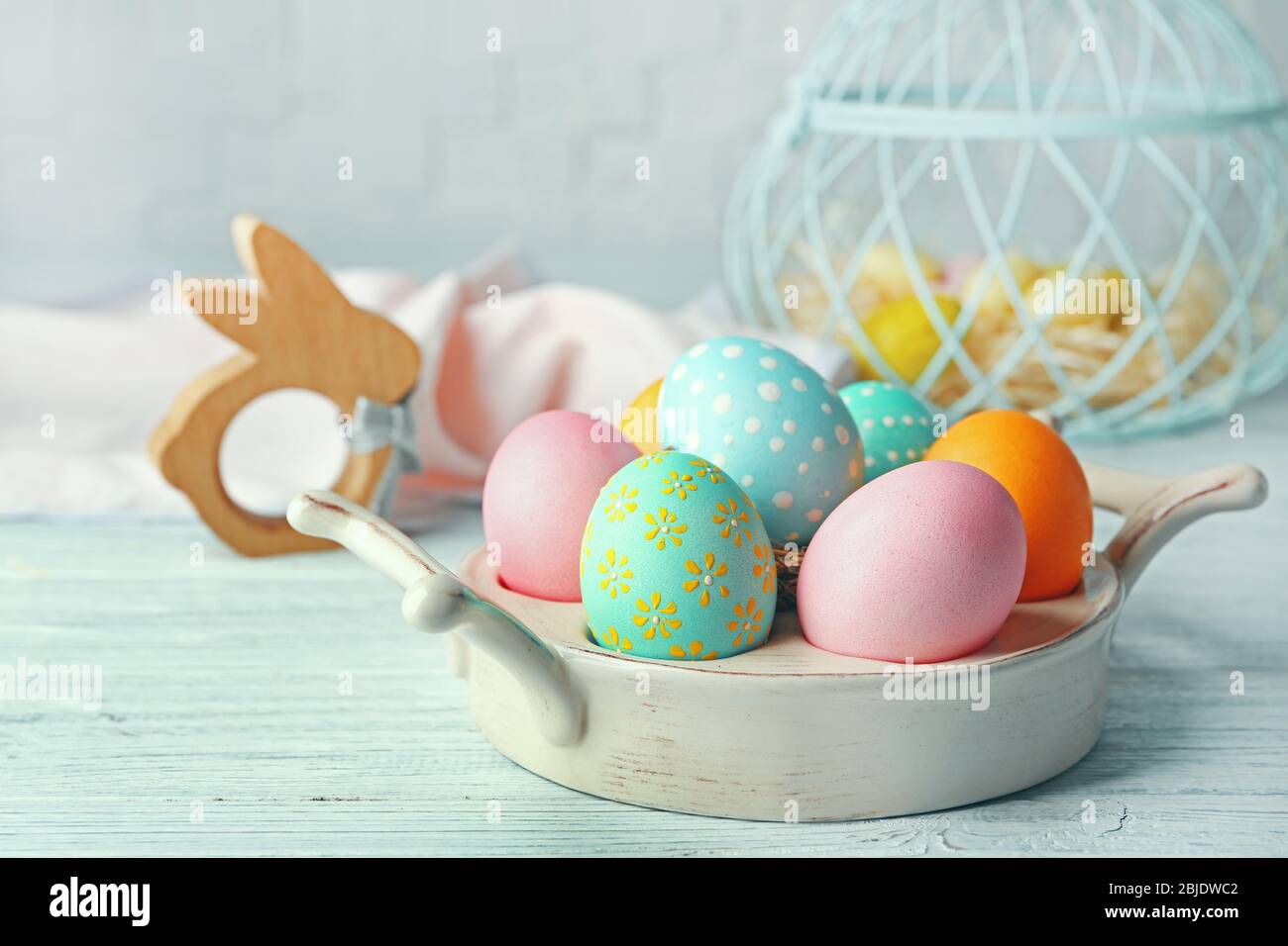 Schüssel mit bunten Ostereiern auf weißem Holztisch Stockfoto