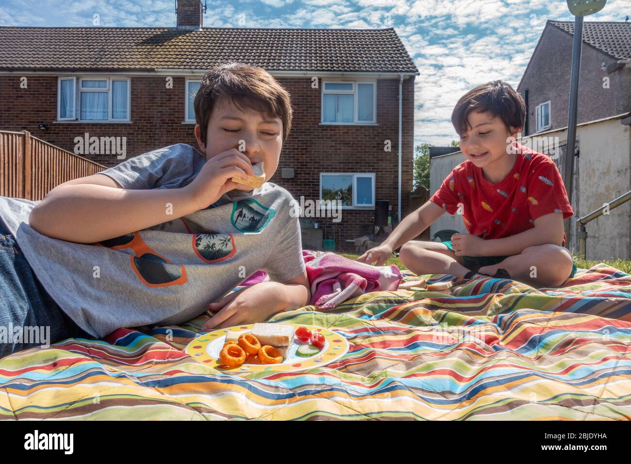 Junge Brüder genießen ein Picknick im Garten an einem warmen, sonnigen Frühlingstag. Stockfoto
