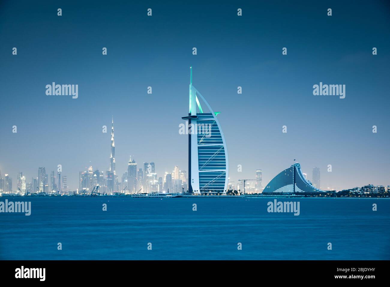 Blick auf die Stadt Dubai über das Meer nach Sonnenuntergang. Dubai, Vereinigte Arabische Emirate. Stockfoto