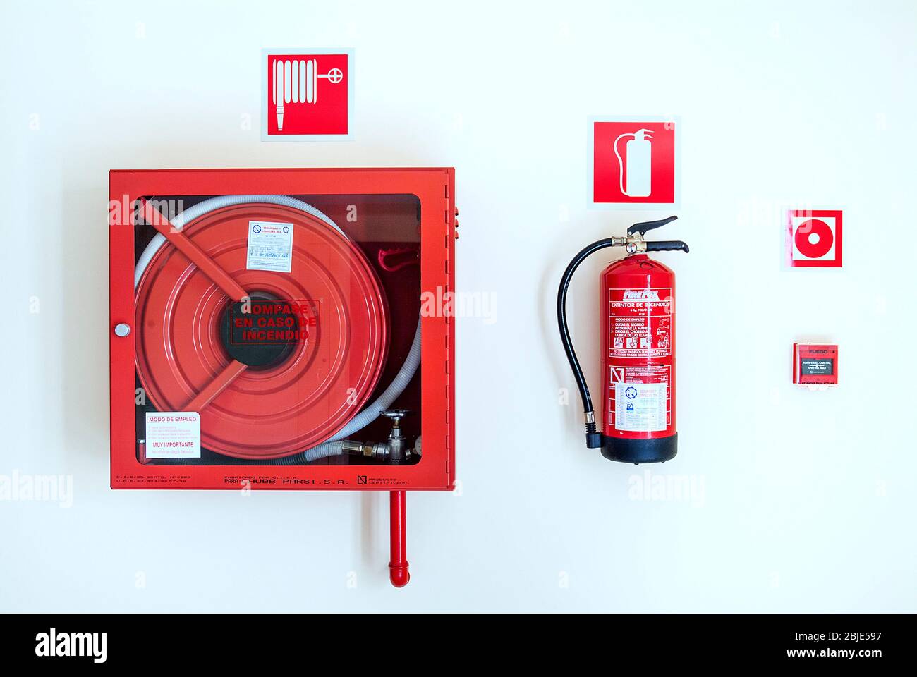 An der Wand montierte Feuerlöscher und Alarmglocke Stockfoto