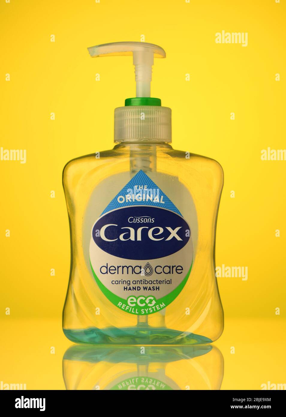 Carex nachfüllbare Flasche antibakterielle Handwäsche leer mit einer kleinen Menge auf einem gelben Hintergrund mit einer Reflexion isoliert. Stockfoto