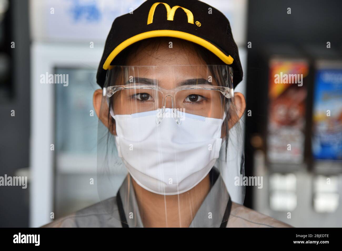 Ein Mitarbeiter von McDonald's, der während der Pandemie Covid-19  vorsorglich eine Schutzmaske und einen Gesichtsschutz trägt.das Restaurant  McDonald's Bangkok bietet nur Mitnahme während der Pandemie Covid-19 an  Stockfotografie - Alamy