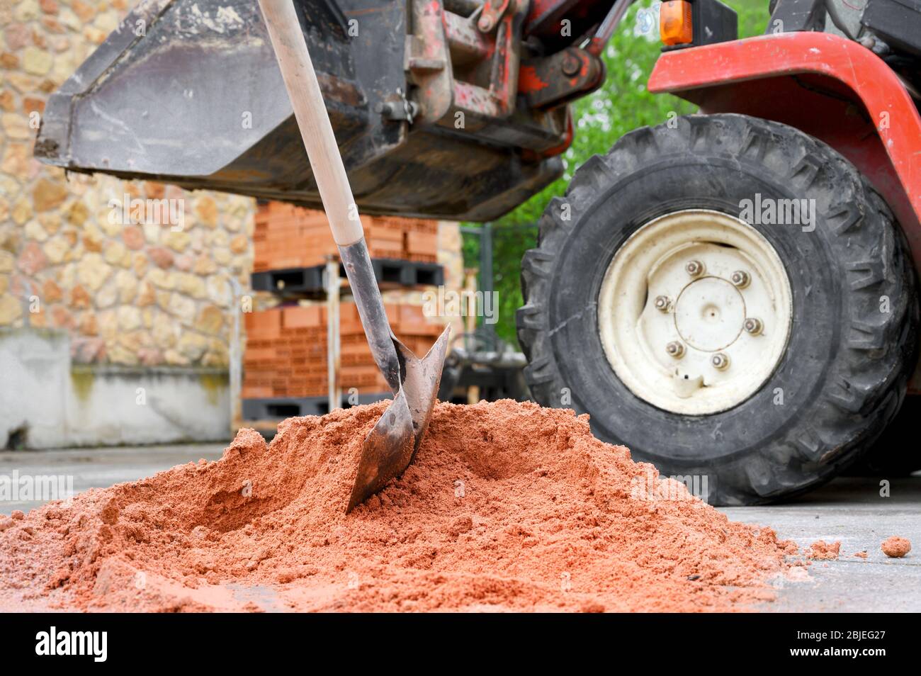 Baustelle Hintergrund mit Schaufel auf Sandhaufen und Bagger im Hintergrund. Stockfoto