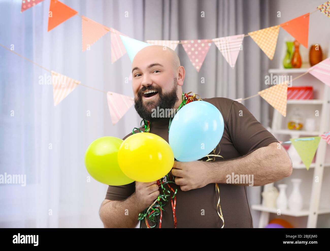 Lustige fette Mann feiert Geburtstag zu Hause Stockfoto
