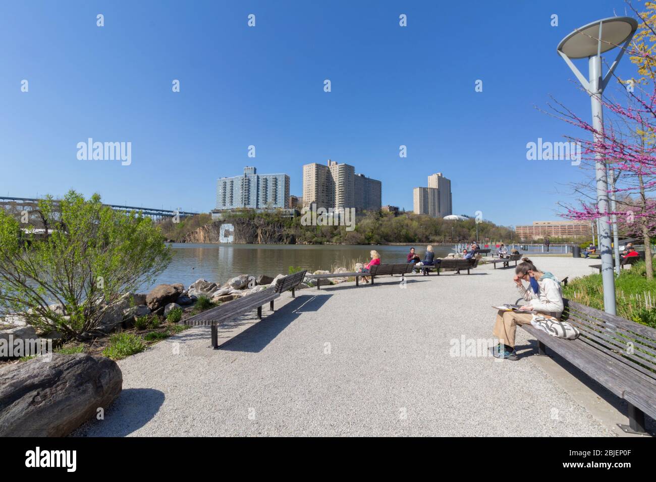 Die Leute genießen einen sonnigen Tag während der Pandemie im Muscota Marsh Park am Harlem River. Blick in Richtung Bronx Stockfoto