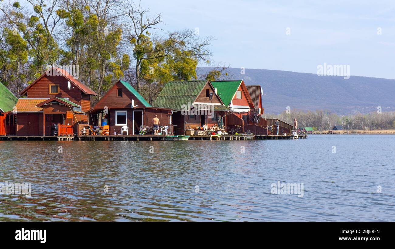 Tata, Ungarn - 03 30 2019: Angler fischen am Derito-See aus kleinen bunten Holzhäusern auf einer Insel. Die Leute kommen hierher, um sich zu entspannen. Stockfoto