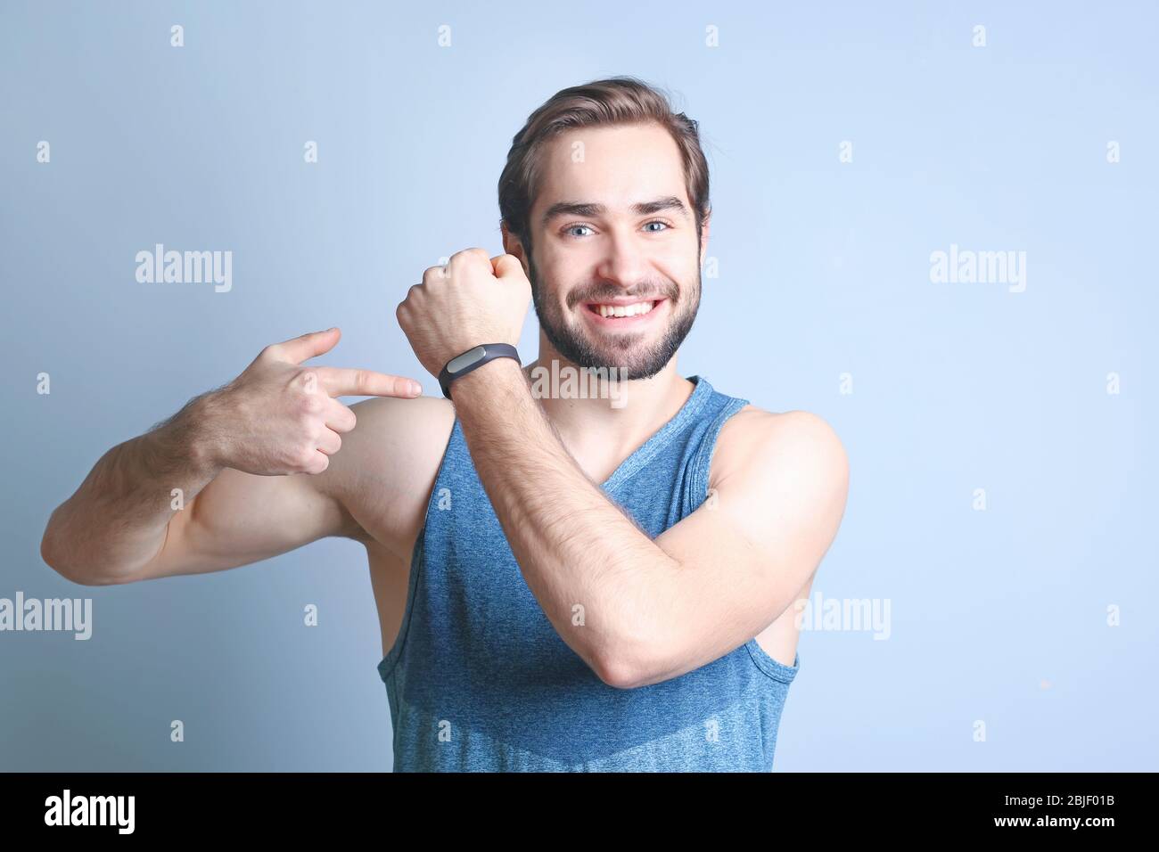 Schöner junger Mann mit Fitness-Tracker auf farbigem Hintergrund Stockfoto