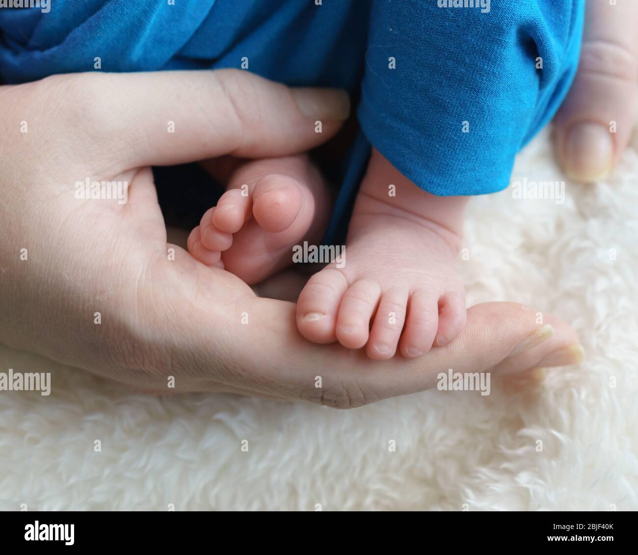 Kleine Kinder Füße in den Händen ihrer Eltern. Pflege der Gesundheit der Neugeborenen Stockfoto