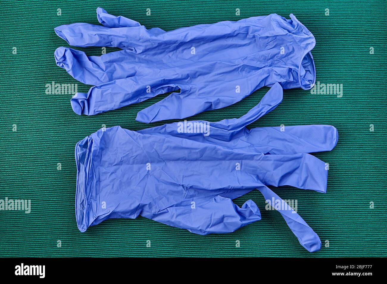 Schutzhandschuhe aus Latex in blau für Sanitäter, grüner Hintergrund. PSA für Gesundheitsdienstleister während der COVID-19-Pandemie. Stockfoto