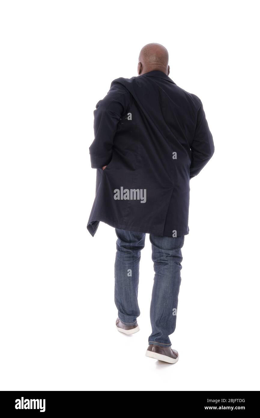 Ganzkörper männliche Figur zurück zur Kamera Ansicht des afroamerikanischen Mann in marineblauen Trenchcoat mit blauen Denim Jeans und lässigen braunen Schuhen Stockfoto