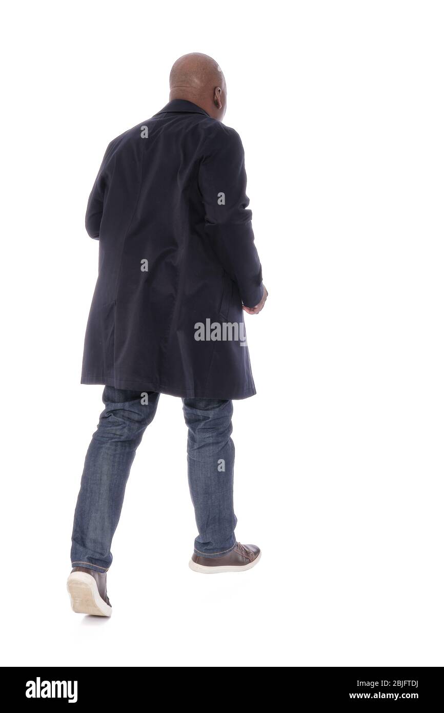 Ganzkörper männliche Figur zurück zur Kamera Ansicht des afroamerikanischen Mann in marineblauen Trenchcoat mit blauen Denim Jeans und lässigen braunen Schuhen Stockfoto