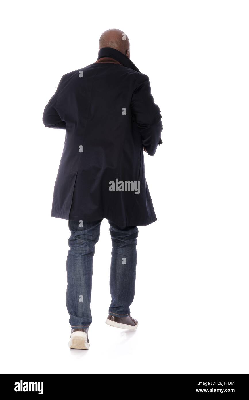 Ganzkörper männliche Figur zurück zur Kamera Ansicht des afroamerikanischen Mann in marineblauen Trenchcoat mit blauen Denim Jeans und lässigen braunen Schuhen Stockfoto
