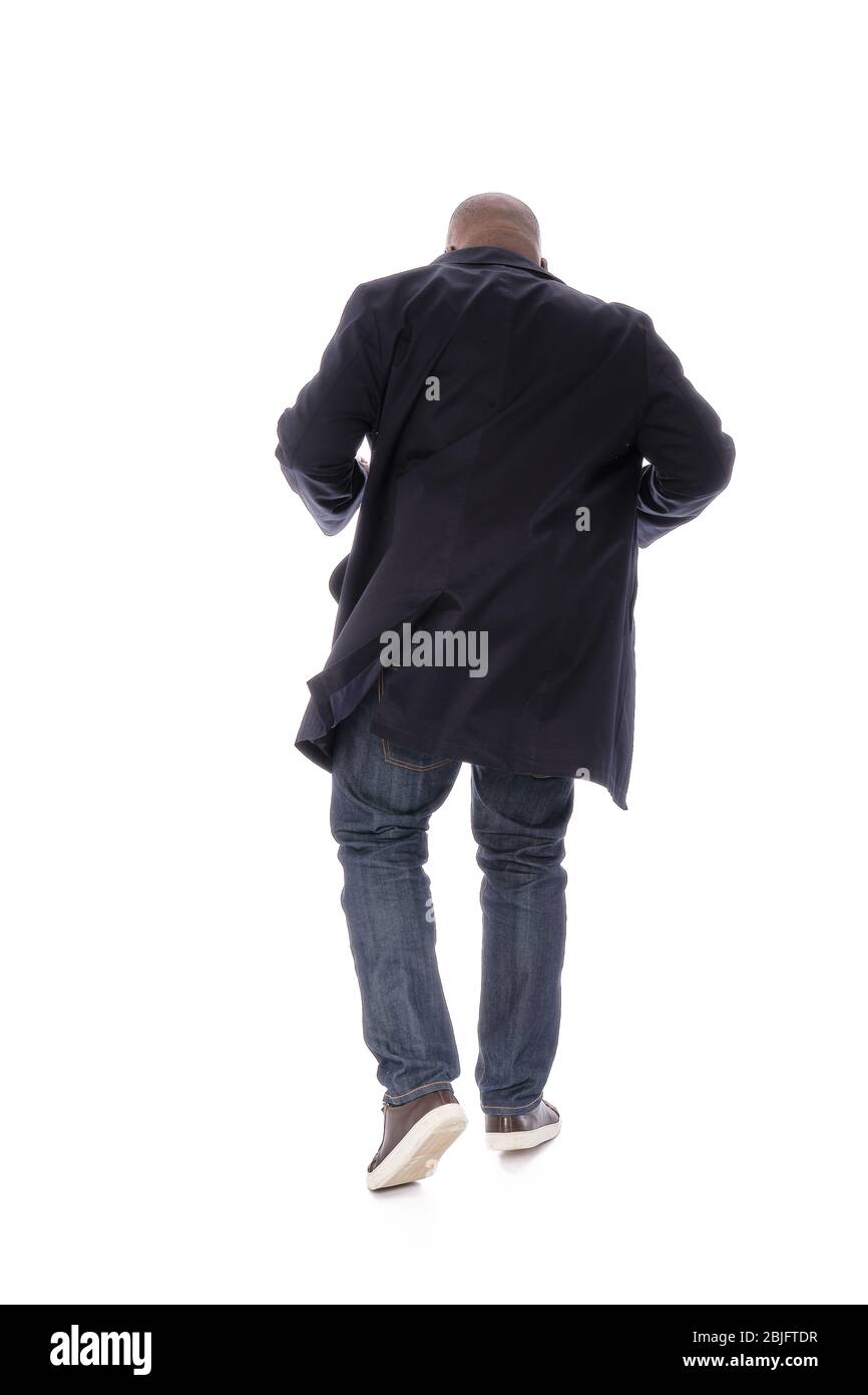 Ganzkörper männliche Figur zurück zur Kamera Ansicht des afroamerikanischen Mann in marineblauen Trenchcoat mit blauen Denim Jeans und lässigen braunen Schuhen Stockfoto