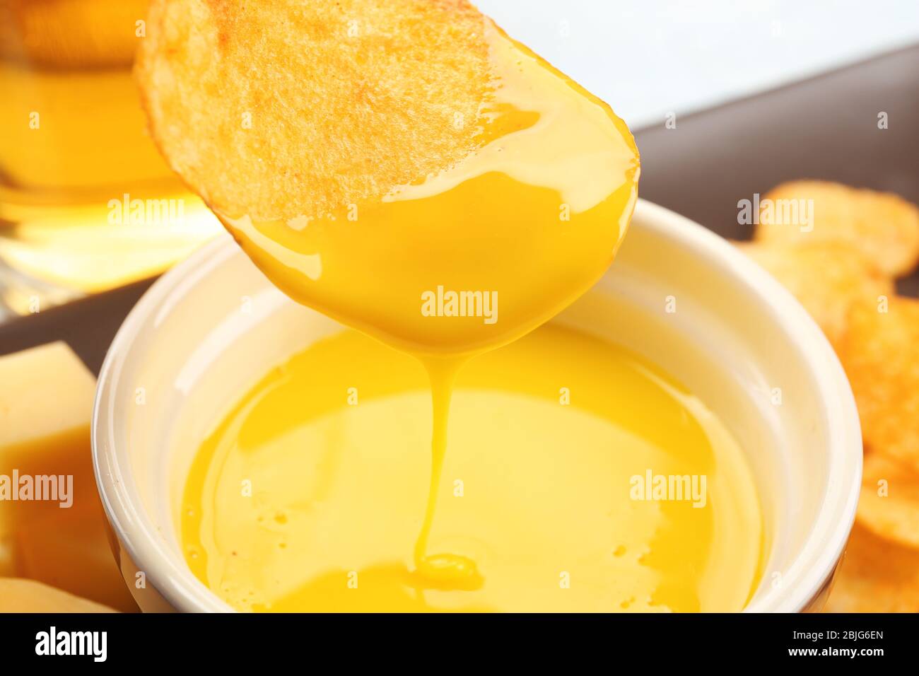 Chips in Schüssel mit cremiger Käsesauce tauchen, Nahaufnahme Stockfoto