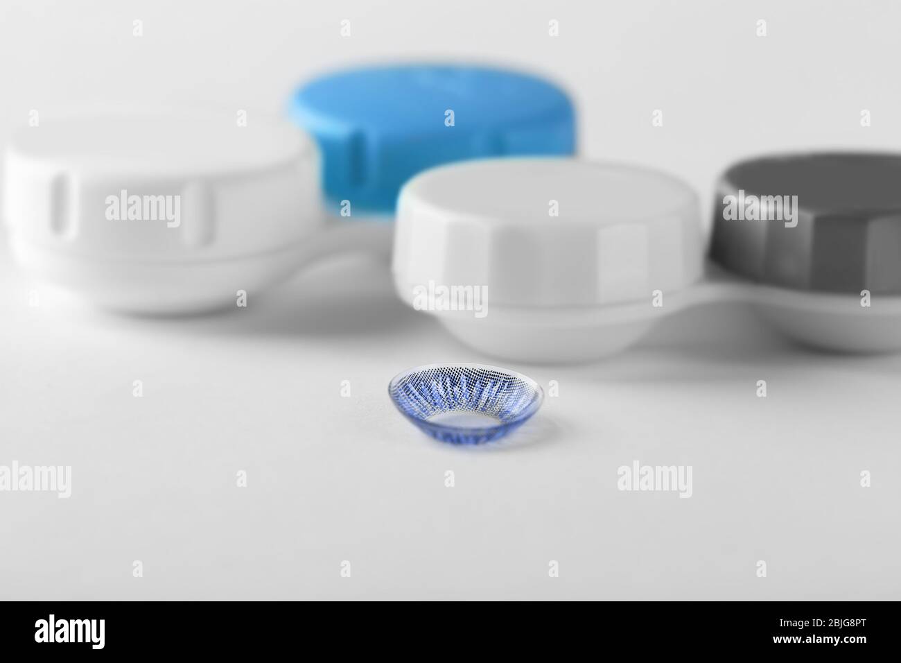 Behälter und blaue Kontaktlinse auf weißem Hintergrund Stockfoto