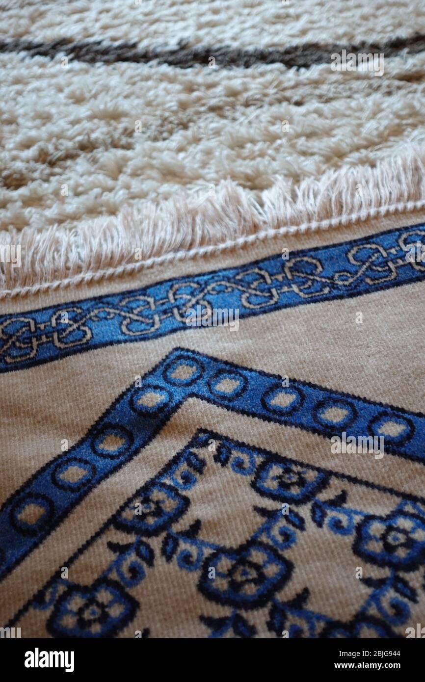 Nahaufnahme eines blauen islamischen Gebetsteppens auf einem modernen türkischen Teppich Stockfoto