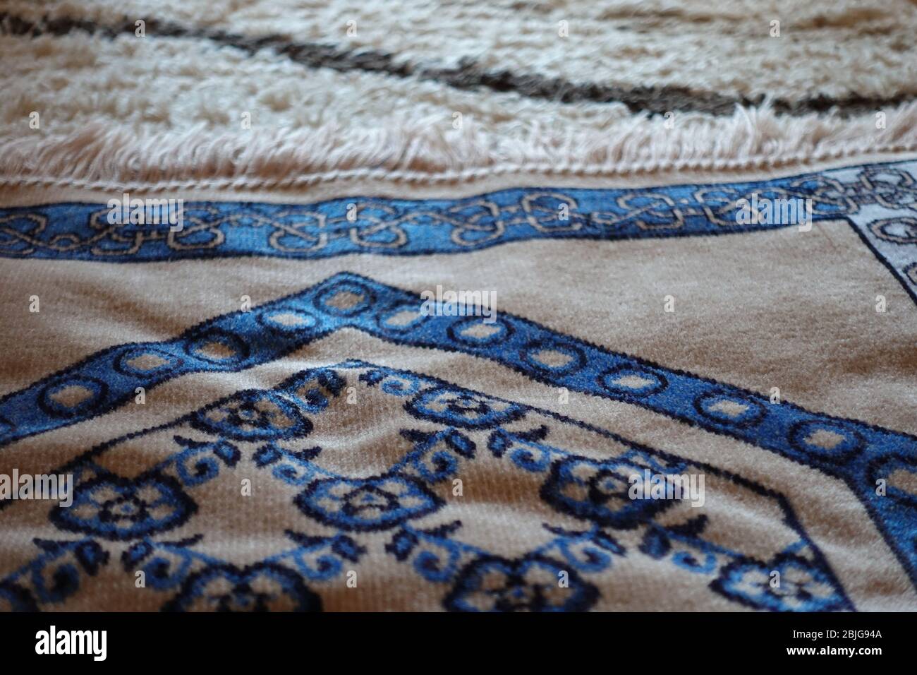 Nahaufnahme eines schönen blauen islamischen Gebetsteppens auf türkischem Teppich an einem sonnigen Tag Stockfoto