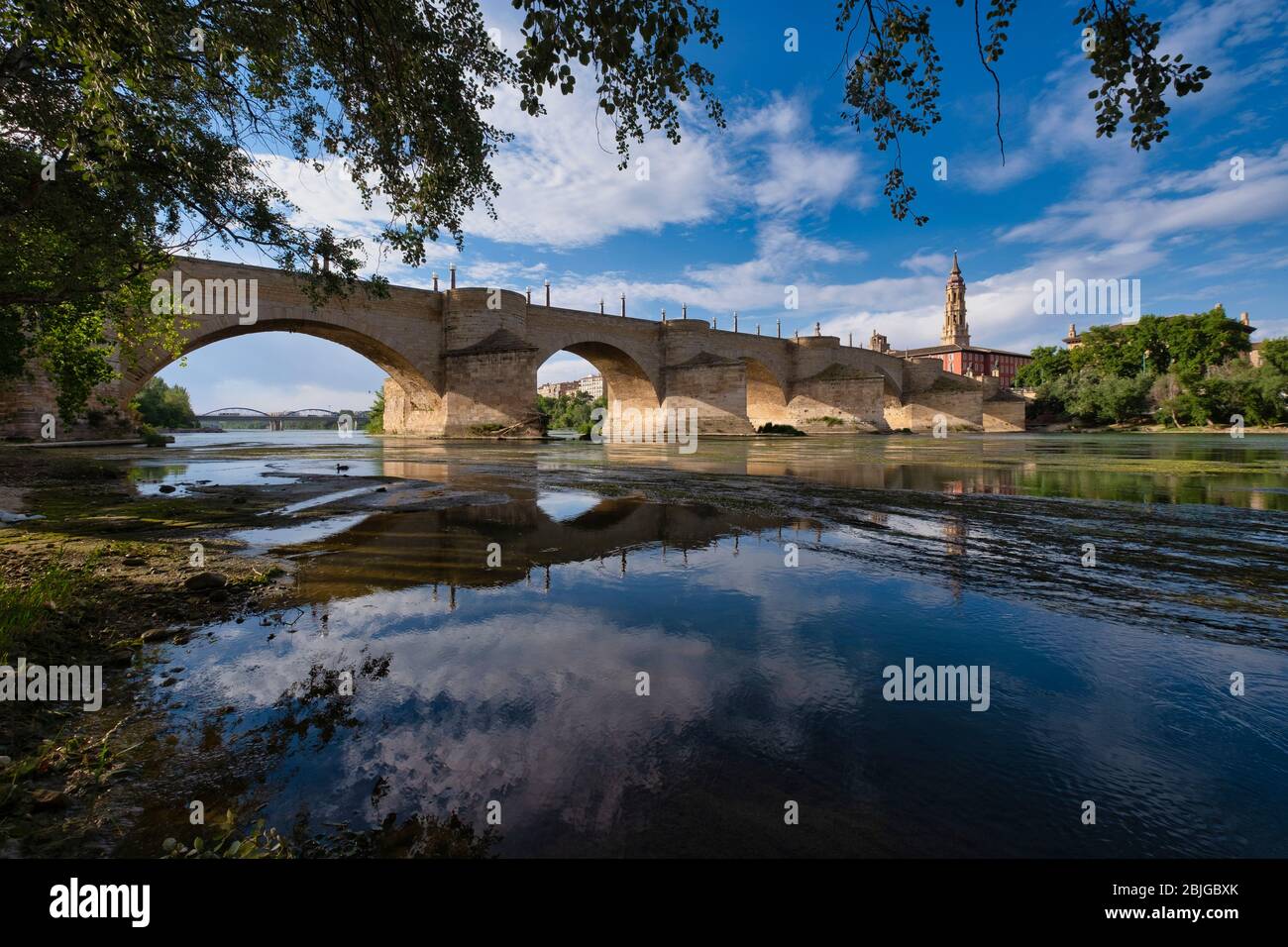 Alte Steinbrücke über den Fluss Ebro mit dem Kirchturm der Kathedrale La Seo aka Catedral del Salvador im Hintergrund, Zaragoza, Spanien Stockfoto