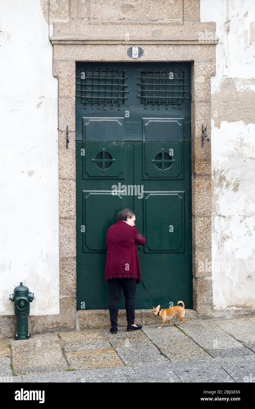 Die alte Frau kehrt nach Hause zurück, nachdem sie ihren chihuahua Hund in der historischen Stadt Guimares im Norden Portugals gelaufen ist Stockfoto