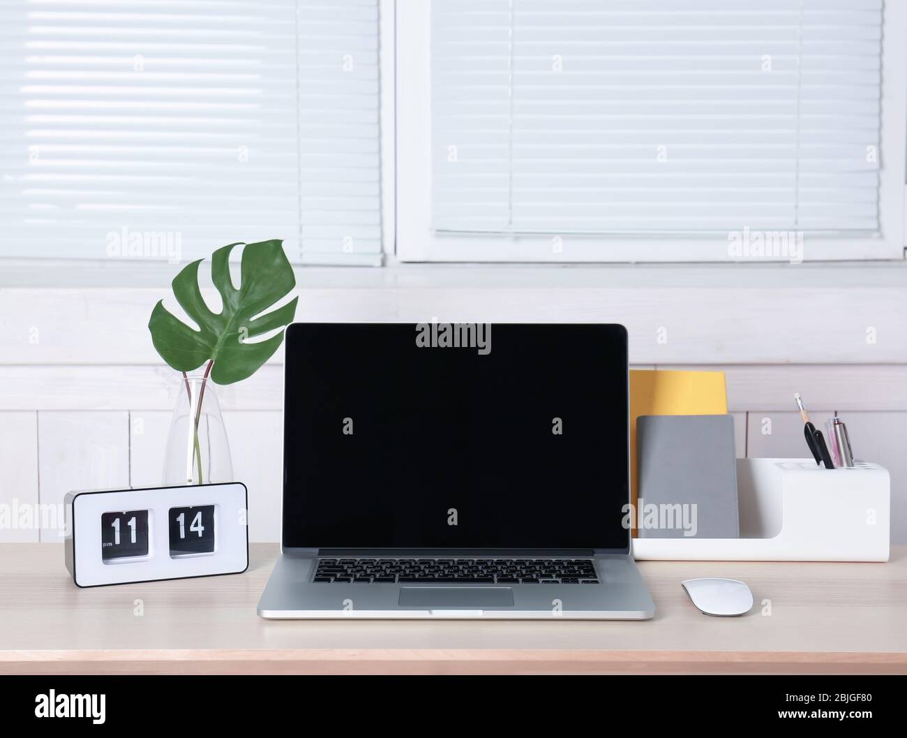 Komfortabler Arbeitsplatz mit modernem Laptop und Jalousien am Fenster Stockfoto