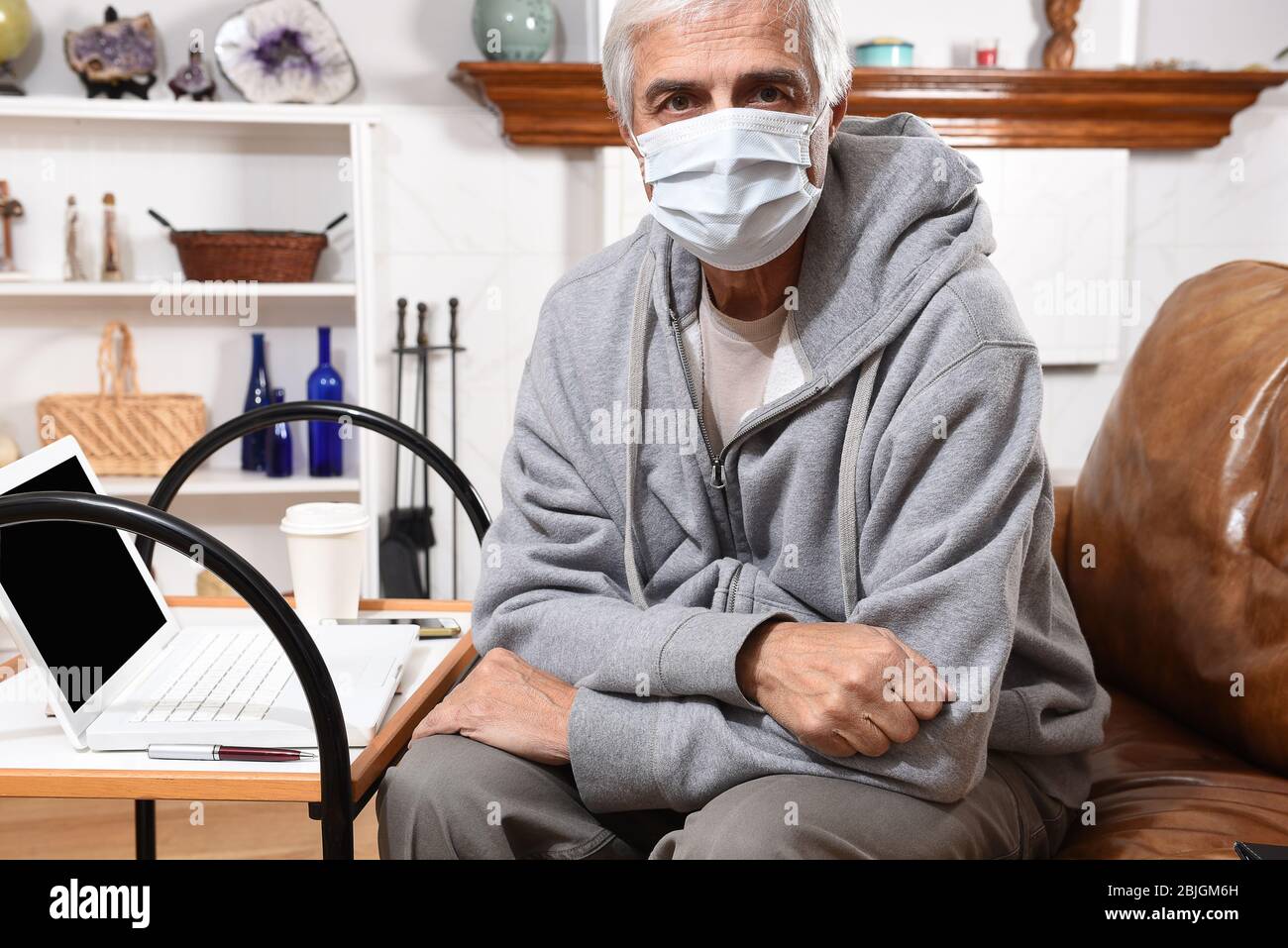Mann fühlt sich nicht gut mit einer COVID-19 Gesichtsmaske während der Arbeit von zu Hause aus. Stockfoto