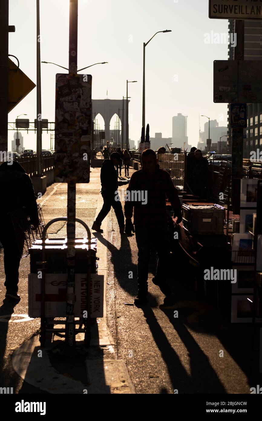 Sommeraufgangszeiten mit Silhouetten von Fußgängern und Händlern auf der Brooklyn Bridge Stockfoto