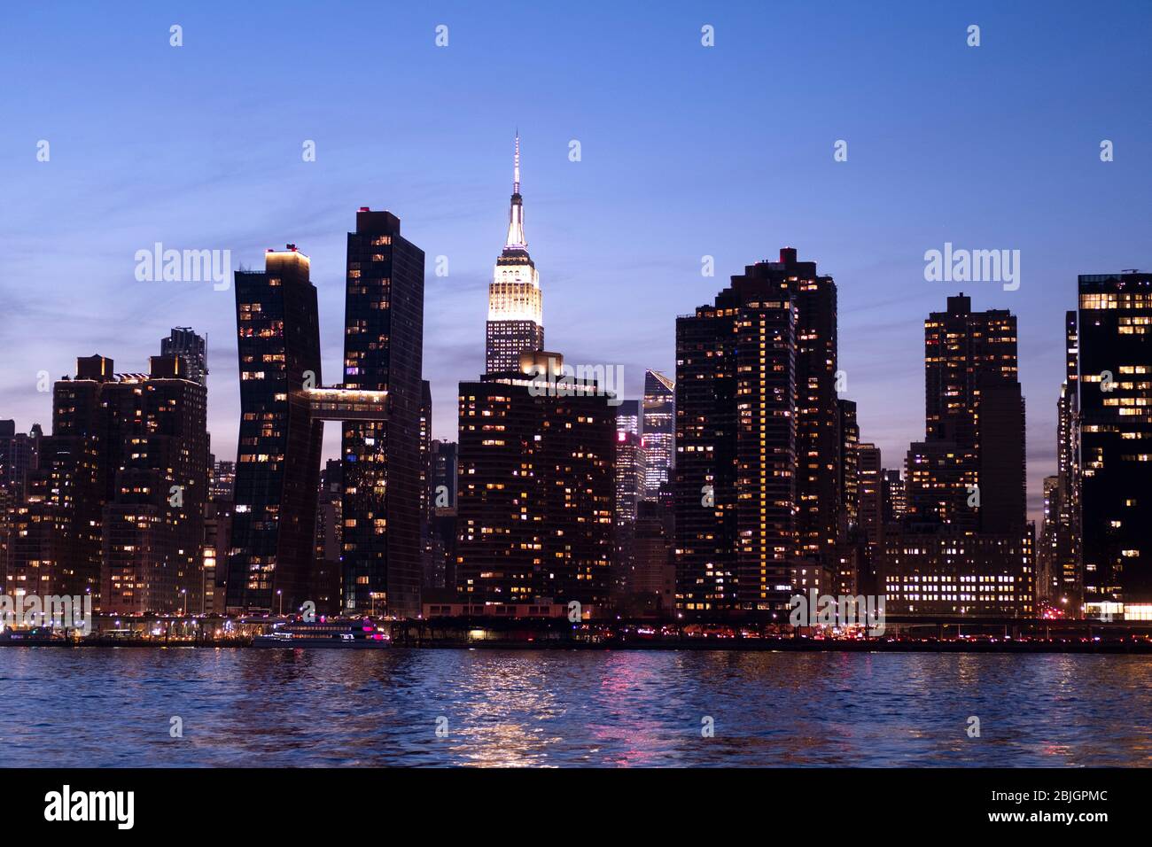 Blick in die Abenddämmerung auf die Skyline von Manhattan mit dem berühmten Empire State Building vom East River in New York City aus gesehen Stockfoto