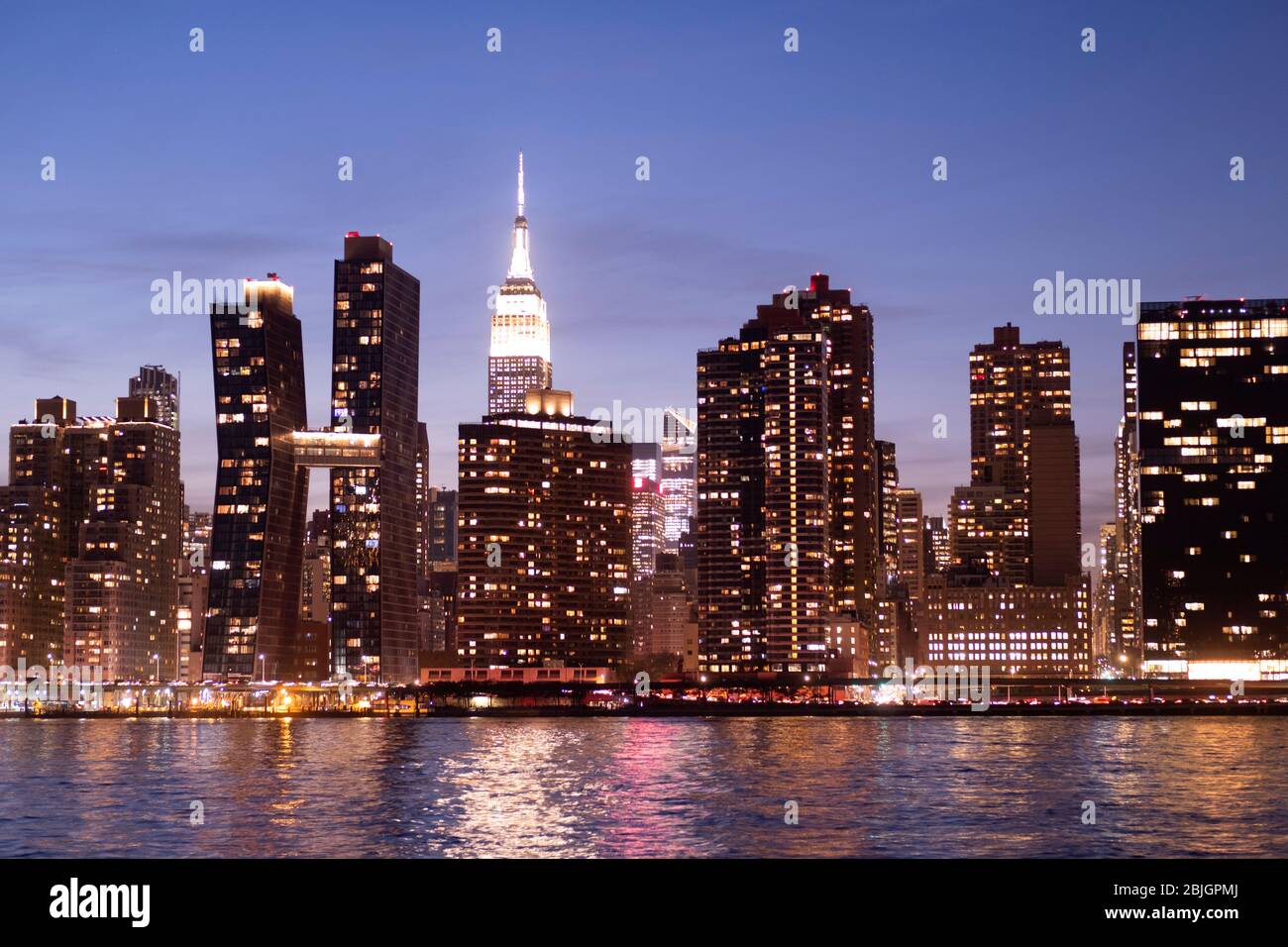 Blick in die Abenddämmerung auf die Skyline von Manhattan mit dem berühmten Empire State Building vom East River in New York City aus gesehen Stockfoto