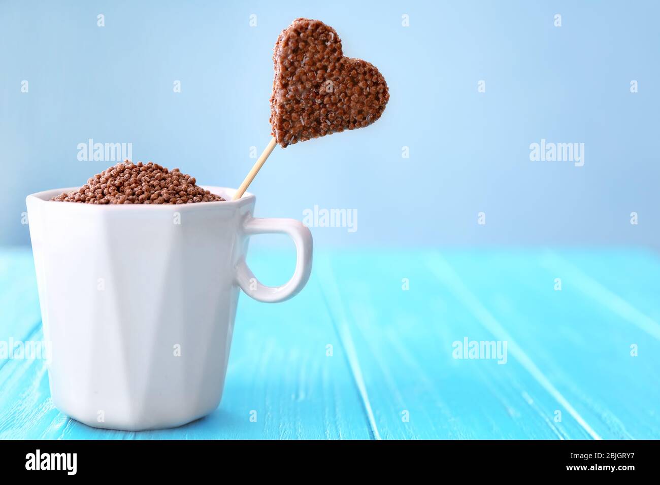 Herzförmiges knuspriges Dessert in Tasse auf Holztisch Stockfoto