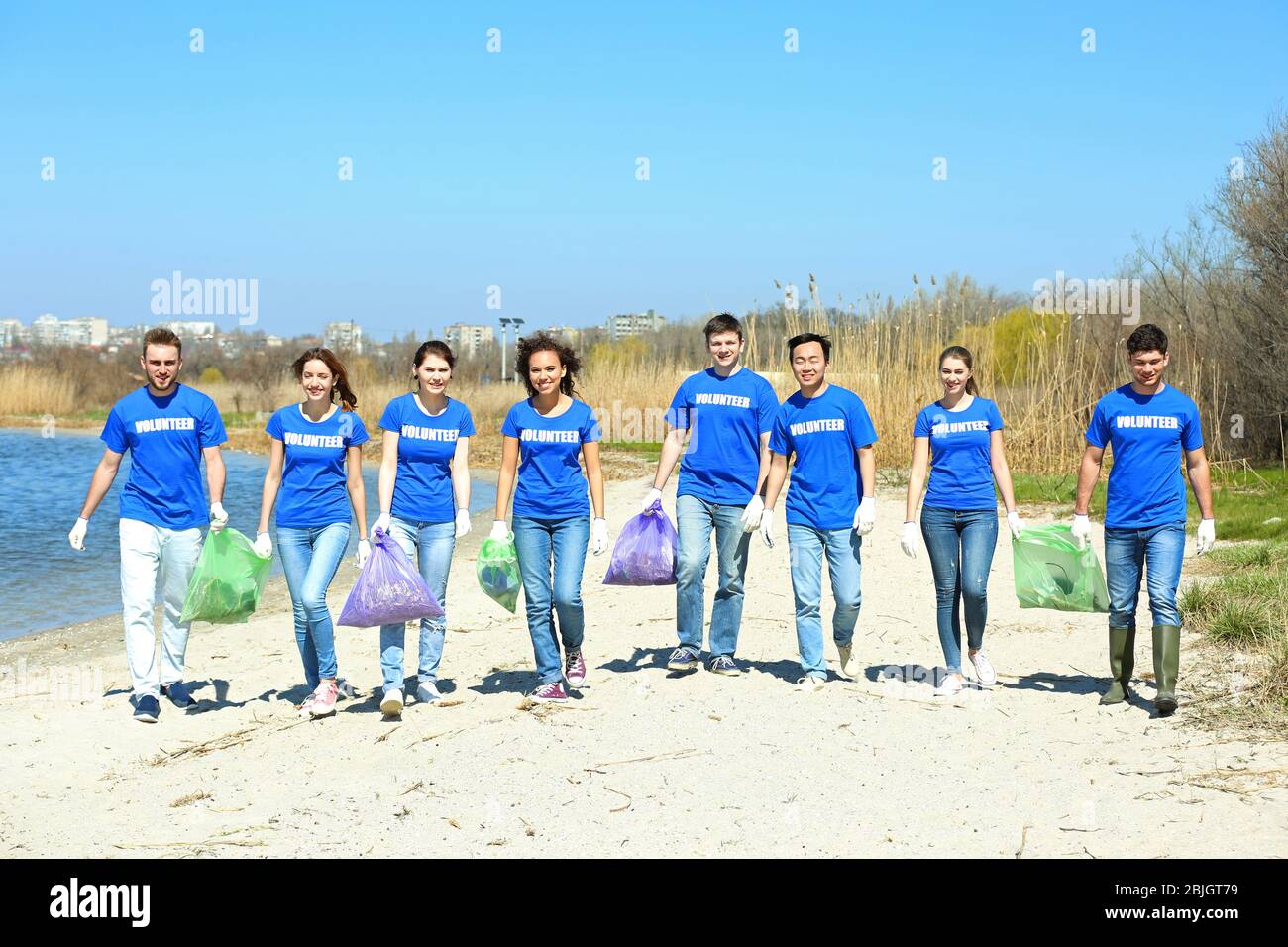 Junge Freiwillige mit Mülltüten in der Nähe des Flusses Stockfoto