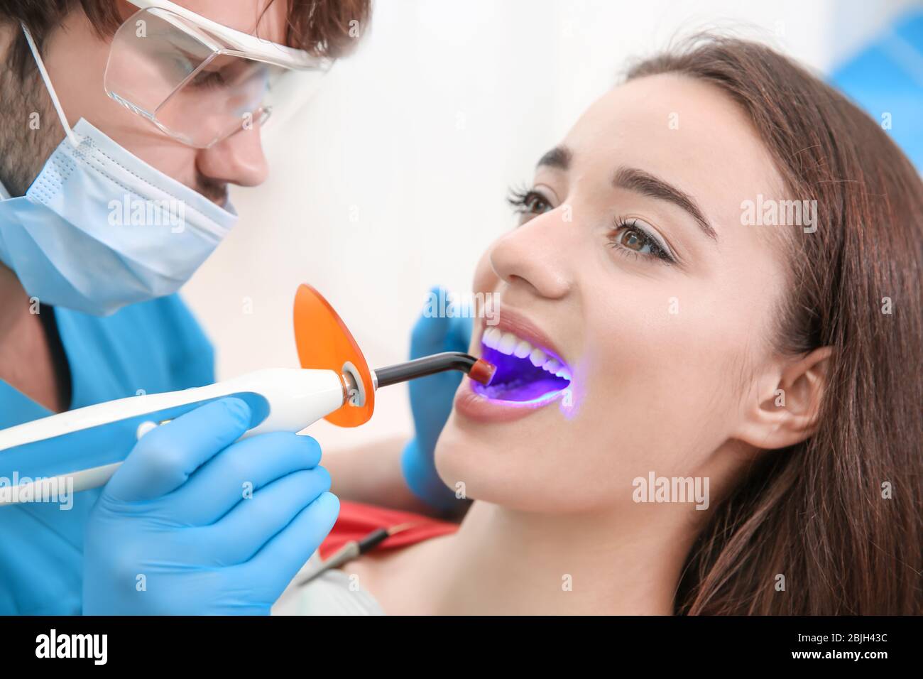 Zahnarzt tun Verfahren mit zahnmedizinischen Härtung mit UV-Licht in der Klinik Stockfoto