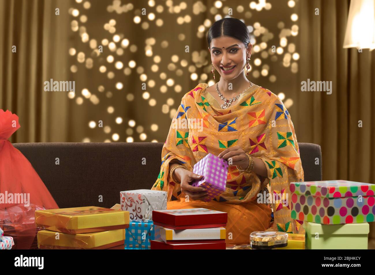 Junge Frau auf einem Sofa mit Geschenkbox Stockfoto